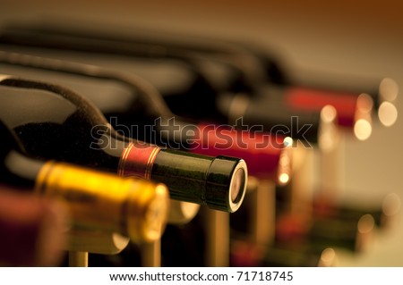 Red wine bottles stacked on wooden racks shot with limited depth of field Royalty-Free Stock Photo #71718745