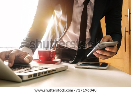 businessman hand using smart phone,mobile p payments online shopping,omni channel,digital tablet docking keyboard computer at office in sun light