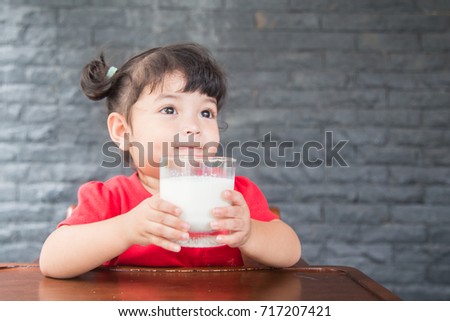 Asian little girl drinking a glass of milk at home,