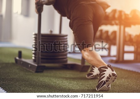 sled push man pushing weights workout exercise at gym