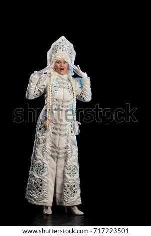 Snow Maiden in a white fur coat and kokoshnik poses on a black background