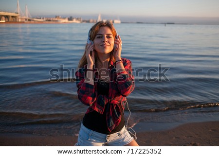 Young woman on beach listening to music, with headphones, the music lover on the beach