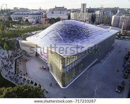 Moscow, Park Zariadye, soaring bridge, city, nature, people, architecture. September 2017.  Multimedia pavilion with glass rooftop. Sunbeams on the glass. Many people walking in the park.