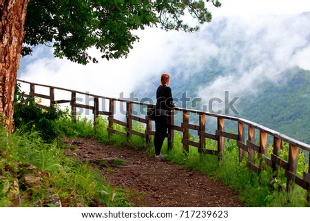 Young woman exploring stunning autumn foggy forest in mountains - nature lovers, hiking or adventure concept