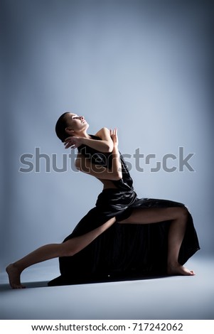 A beautiful athletic girl in a black dress is dancing