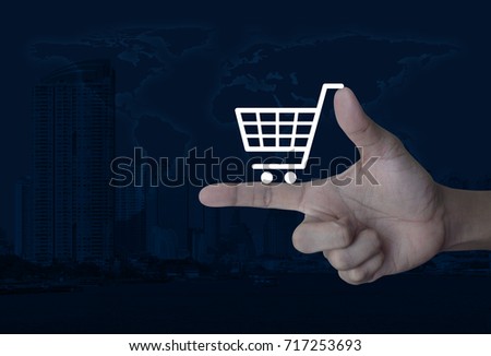 Shopping cart icon on finger over world map and modern city tower, Shop online concept, Elements of this image furnished by NASA