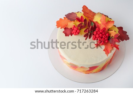 Art cake with whipped yellow, orange and green cream, decorated with autumn leaves from mastic. Picture for a menu or a confectionery catalog.
