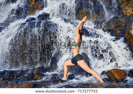 Horizontal picture of a woman practicing warrior yoga pose standing in a water