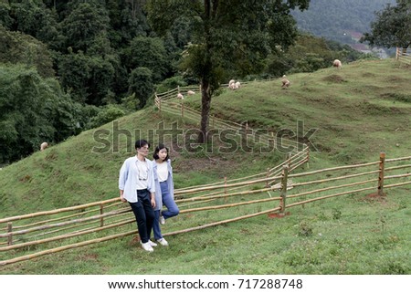 A view shot of young woman with her boyfriend on grass field. Couple enjoying on hill. Pre-wedding concept.