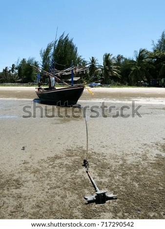Fishing boat anchored on the sandy beach with blue sky background in small fisherman's village , Pranburi, Hua Hin, Thailand.