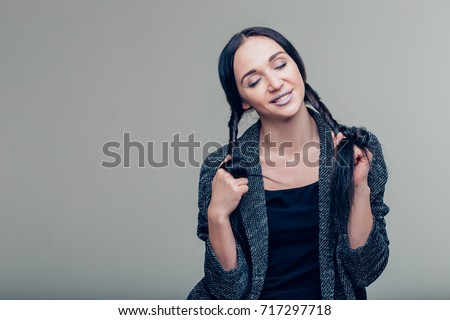Young attractive girl holding myself for long braids. Portrait of beautiful smiling woman with beauty hair. A wide braid