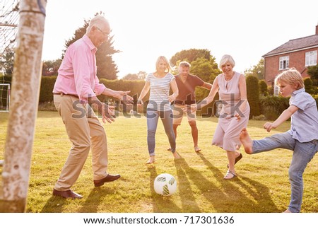 Multi generation family playing football in the garden Royalty-Free Stock Photo #717301636