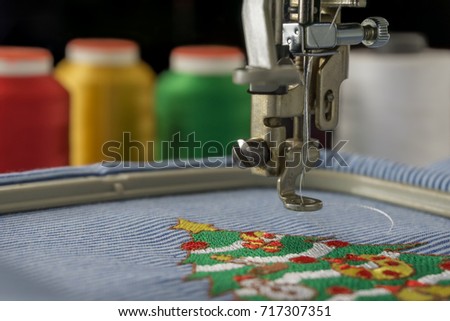 Macro picture of embroidery machine finish work christmas tree design on fabric stripes white and blue 
