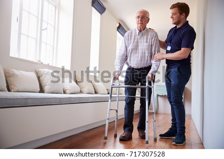 Senior woman using a walking frame with male nurse at home Royalty-Free Stock Photo #717307528