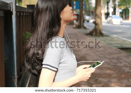Young girl listening to music on a smartphone in Vietnam