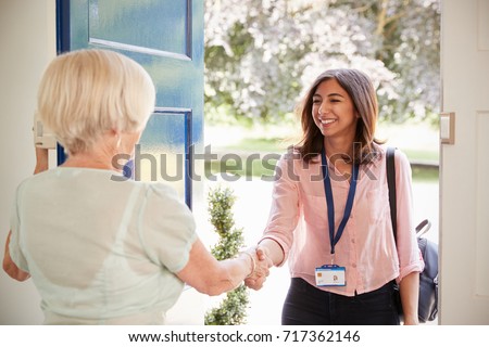 Senior woman greeting female care worker making home visit Royalty-Free Stock Photo #717362146