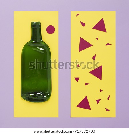 Green glass bottle lying on yellow piece of paper. Trendy colors paper craft concept. Object photography.