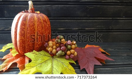 Pumpkin with leaves and berries, wooden background.