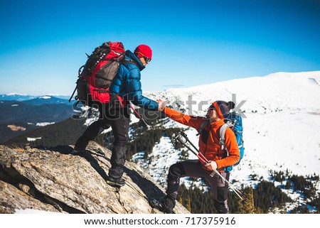 Climber helping teammate climb, the man with the backpack reached out a helping hand to his friend. Royalty-Free Stock Photo #717375916