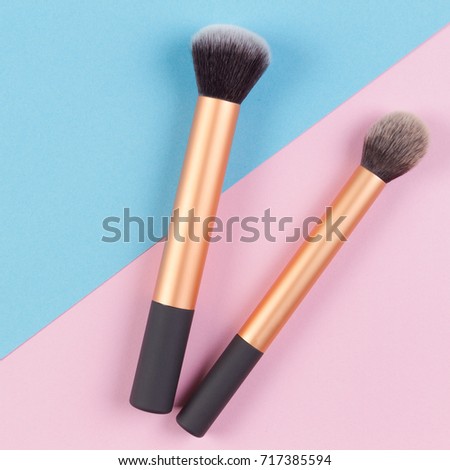 Make up brushes on pink and blue background. Top view.