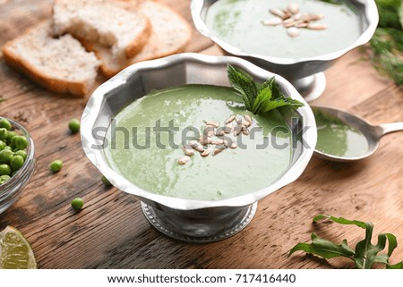 Delicious puree from green peas in bowl on wooden table
