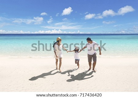 Picture of Asian parents spending time with their daughter while walking together on the beach