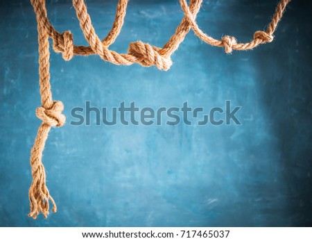 Jute rope hanging from above on dark blue background.