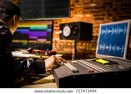 asian male professional sound engineer working in digital recording, broadcasting, editing studio. focus on mixer fader
