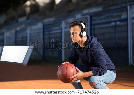 Young sportsman basketball player posing with ball and headphone