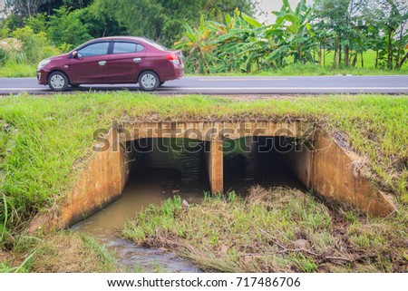 Reinforced concrete box culverts under the asphalt road. Box culvert is a structure that allows water to flow under a road, railroad, trail, or similar obstruction from one side to the other side. Royalty-Free Stock Photo #717486706
