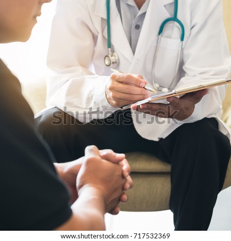 Doctor consulting male patient, working on diagnostic examination on men's health disease or mental illness, and writing on prescription record information document in clinic or hospital office Royalty-Free Stock Photo #717532369