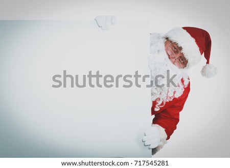 Happy Santa Claus looking out from behind the blank sign isolated on white background .