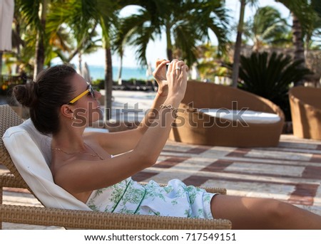 Tourist woman taking travel picture with phone. Lady relaxing near pool. Summer luxury holidays.