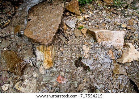 A shallow stream flows through limestone rocks and pebbles