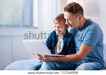Caring father watching cartoons with his son on laptop
