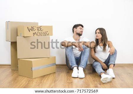 The man and woman sit on the floor near carton boxes