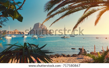 Famous, empty and beautiful Cala d'Hort beach, in summer very popular, sandy coast have a fantastic view of mysterious island of Es Vedra. Moored vessels on bay. Ibiza Island, Balearic Islands. Spain Royalty-Free Stock Photo #717580867