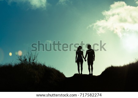 Love and relationships.  Young couple holding hands walking together on a country road. 