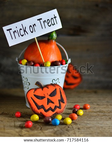 Trick or treat - poster in a bucket with sweets and pumpkin, carrot for halloween with colorful candy, old wooden background copy of space