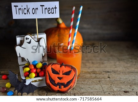 Gingerbread on Halloween with multi-colored sweets, pumpkin juice and a poster - Trick or treat, wooden old background