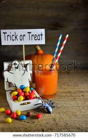 Gingerbread on Halloween with multi-colored sweets, pumpkin juice and a poster - Trick or treat, wooden old background
