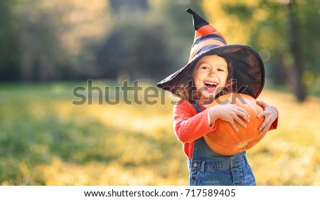 happy child girl with pumpkin outdoors in halloween