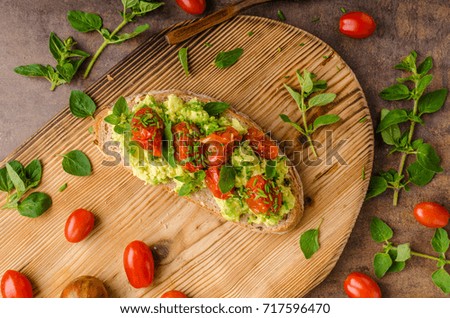 Avocado spread with tomatoes, roasted tomatoes and herbs on top