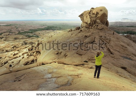 The girl takes pictures of a beautiful, quaint rock in the desert mountains