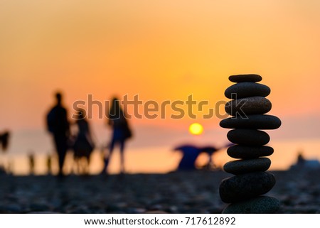 Stones pyramid on sand symbolizing zen, harmony, balance. Black sea at sunset in the background.