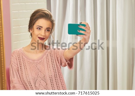 Woman smiling and taking selfie. Attractive young female holding phone. How to get more subscribers.
