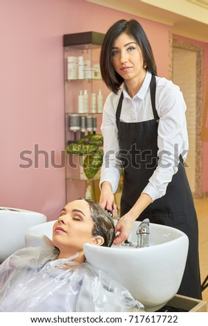 Beautician washing head of customer. Woman working in hair salon. Shampoo recommended by stylists.