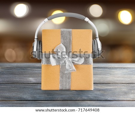 Christmas music concept. Gift box with headphones on blurred background