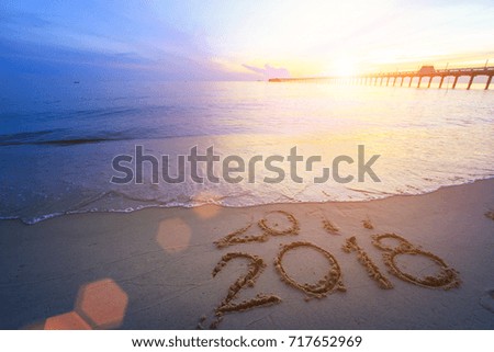 New Year 2018 is coming concept - inscription 2017 and 2018 on a beach sand, the wave is starting to cover the digits 2017 Royalty-Free Stock Photo #717652969