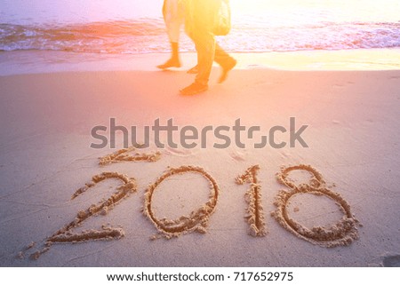New Year 2018 is coming concept - inscription 2017 and 2018 on a beach sand, the wave is starting to cover the digits 2017 Royalty-Free Stock Photo #717652975